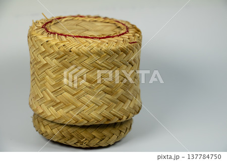 Traditional Thai woven bamboo container used to store cooked sticky rice. Handmade cylindrical basket with natural texture, isolated on white background. Traditional Thai woven bamboo container used to store cooked sticky rice. Handmade cylindrical basket with natural texture, isolated on white background. 137784750