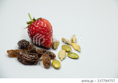 Fresh ripe strawberry with dried raisins and pumpkin seeds isolated on white background. Healthy snack ingredients with natural texture and copy space. Fresh ripe strawberry with dried raisins and pumpkin seeds isolated on white background. Healthy snack ingredients with natural texture and copy space. 137784757