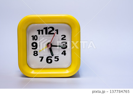 Bright yellow square alarm clock with black numbers isolated on white background. Time management, punctuality, deadline and schedule concept, studio shot with copy space. Bright yellow square alarm clock with black numbers isolated on white background. Time management, punctuality, deadline and schedule concept, studio shot with copy space. 137784765
