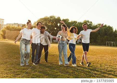 Getting ready for playing football. Young friends are having fun on the field with soccer ball 137785005