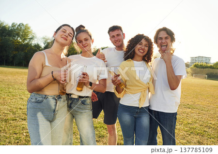 Enjoying weekend, with beer. Young friends are having fun on the field Enjoying weekend, with beer. Young friends are having fun on the field 137785109