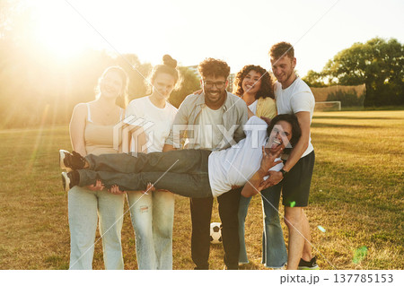Positive facial expressions. Young friends are having fun on the field with soccer ball 137785153