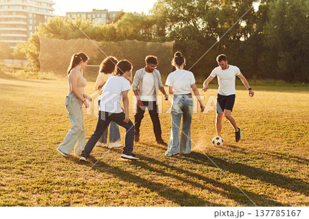 Illuminated by sunlight. Group of friends are playing soccer on the field Illuminated by sunlight. Group of friends are playing soccer on the field 137785167