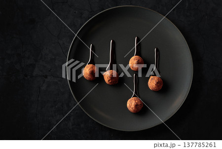 Chocolate truffles on a black plate. Chocolate truffles on a black plate. 137785261
