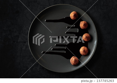Chocolate truffles on a black plate. 137785263