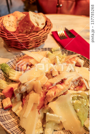 Caesar salad with grilled chicken and parmesan cheese served with French baguette in a restaurant in Paris, France Caesar salad with grilled chicken and parmesan cheese served with French baguette in a restaurant in Paris, France 137785268