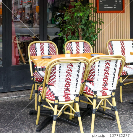 Paris cafe chairs and table on a sidewalk, inviting visitors to enjoy an outdoor dining experience Paris cafe chairs and table on a sidewalk, inviting visitors to enjoy an outdoor dining experience 137785277