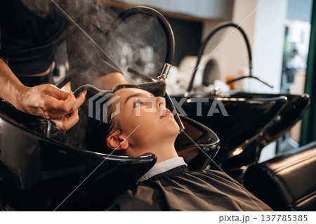 Doing all the washing. Woman is in a beauty salon with hair stylist Doing all the washing. Woman is in a beauty salon with hair stylist 137785385
