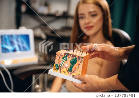 Explaining the hair growth process, holding model. Woman is in a beauty salon with hair stylist 137785481
