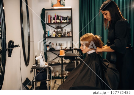 Woman is in a beauty salon with hair stylist 137785483