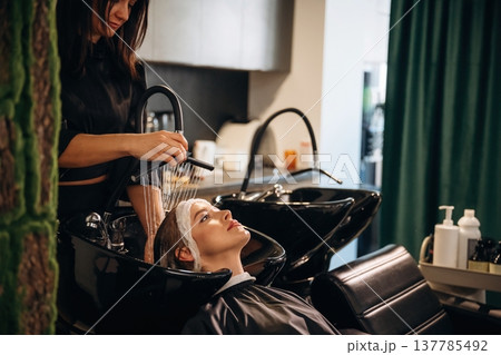 Lying down, washing the hair. Woman is in a beauty salon with hair stylist 137785492