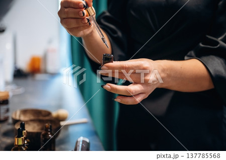 Close up view of hands of hairdresser that is taking liquid for increasing the hair growth Close up view of hands of hairdresser that is taking liquid for increasing the hair growth 137785568