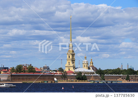 Russia, Petersburg, June 29, 2019. Spit of Vasilyevsky Island. The photo shows the Peter and Paul Fortress on the bank of the Neva against the sky and a pleasure boat Russia, Petersburg, June 29, 2019. Spit of Vasilyevsky Island. The photo shows the Peter and Paul Fortress on the bank of the Neva against the sky and a pleasure boat 137785630