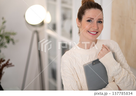 Waist up of smiling woman with hair bun in white sweater Waist up of smiling woman with hair bun in white sweater 137785834