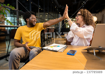 Professional man in wheelchair and woman high fiving celebrating project achievement Professional man in wheelchair and woman high fiving celebrating project achievement 137785889