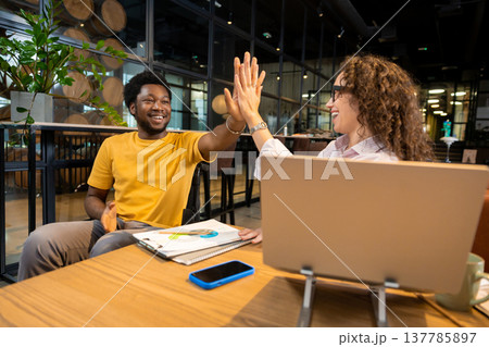 African American man in wheelchair and Caucasian woman giving high five 137785897