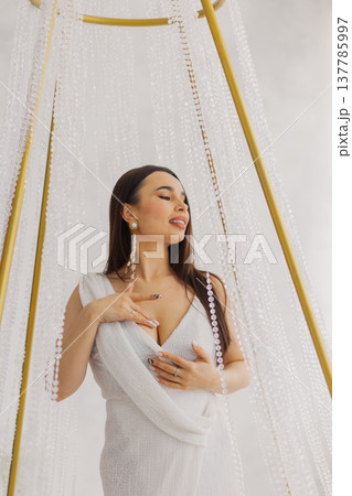 Young beautiful woman posing near gilded crystal Young beautiful woman posing near gilded crystal 137785997