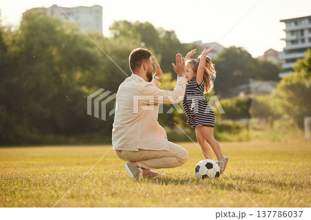Giving high five, teamwork. Father with his little daughter are on the field 137786037