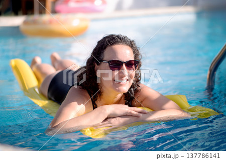 Happy woman relaxing on a yellow inflatable...の写真素材 [137786141] - PIXTA