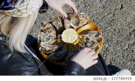Close-up of a girl taking an oyster from a tray 137786459