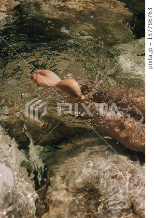 Close-up top view of a young woman's bare feet in a water. 137786763