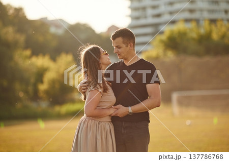 Looking at each other with love. Couple have a walk on the summer field Looking at each other with love. Couple have a walk on the summer field 137786768