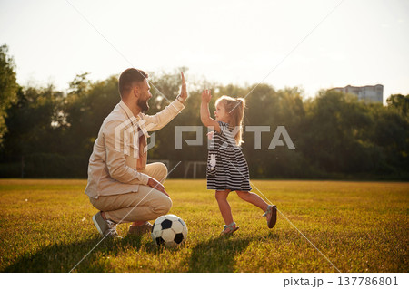 Great teamwork, high five, soccer players. Father with his little daughter are on the field 137786801