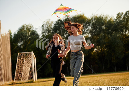 Females are with kite, running. Two kids are having fun on the summer field Females are with kite, running. Two kids are having fun on the summer field 137786994