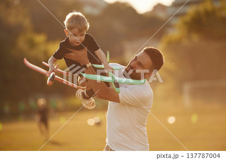 Come fly with me, holding kid in hands, toy plane. Happy father with son on the field 137787004