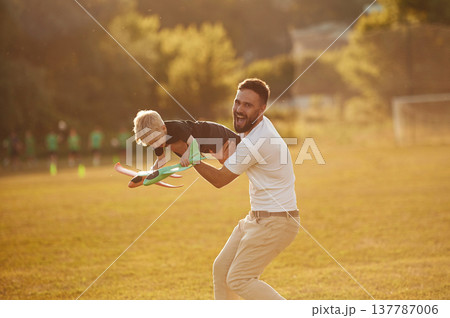 Come fly with me, holding kid in hands, toy plane. Happy father with son on the field 137787006