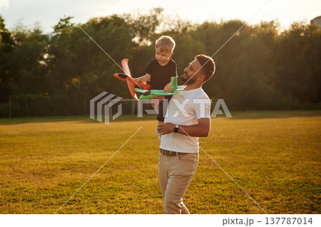 Cheerful, with toy plane, playing. Happy father with son on the field 137787014