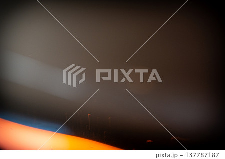 Abstract image featuring blurred light streaks in orange and blue against a dark background, creating a sense of depth and movement in a minimalist composition 137787187