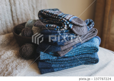 Hand knitted socks with needles and yarn ball in a basket. Concept for handmade and hygge slow life. Hand knitted socks with needles and yarn ball in a basket. Concept for handmade and hygge slow life. 137787224
