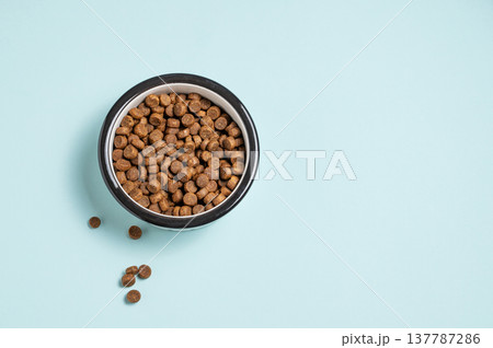 A bowl of dry dog food on a isolated blue background. 137787286