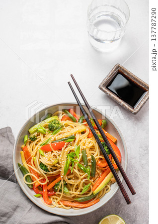 Stir fry wok noodles with vegetables in a plate on a light concrete background with chopsticks Stir fry wok noodles with vegetables in a plate on a light concrete background with chopsticks 137787290