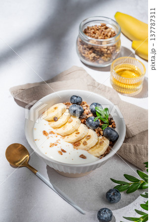 Natural greek yogurt with granola, blueberry and banana in a bowl on a light concrete background 137787311