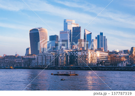 Morning light bathes the modern skyline of London as the Thames river gently flows by. Skyscrapers rise above the city, creating a stunning urban landscape. Morning light bathes the modern skyline of London as the Thames river gently flows by. Skyscrapers rise above the city, creating a stunning urban landscape. 137787319