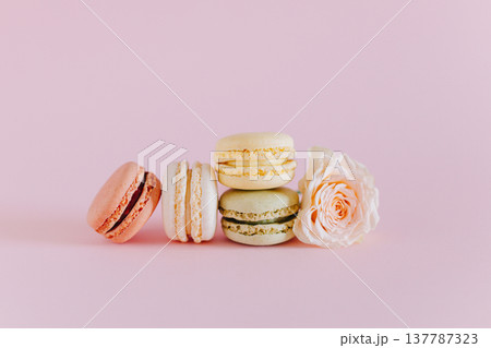 Tasty french macarons with tender rose flowers on a pink pastel background. Tasty french macarons with tender rose flowers on a pink pastel background. 137787323