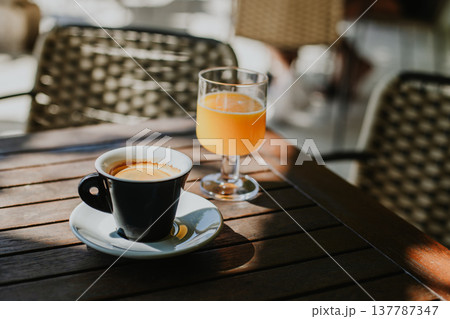 Cup of black coffee and fresh orange juice on a table in a street cafe. Cup of black coffee and fresh orange juice on a table in a street cafe. 137787347