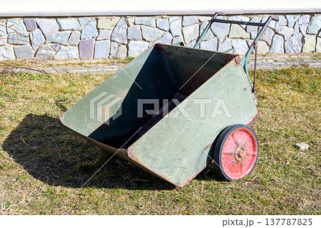 Vintage metal garden cart with red wheels on grass 137787825