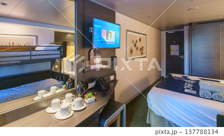 Tokyo, Japan - Oct 2 2024, panoramic view of interior of living cabin with four beds, illuminated by bedside lamps and overhead light, without people, on the MSC Bellissima cruise ship, Tokyo, Japan Tokyo, Japan - Oct 2 2024, panoramic view of interior of living cabin with four beds, illuminated by bedside lamps and overhead light, without people, on the MSC Bellissima cruise ship, Tokyo, Japan 137788134