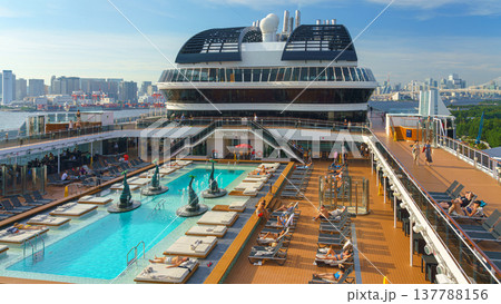 Tokyo, Japan - Oct 2 2024, panoramic view of the public outdoor pool on the upper deck of the MSC Belissima cruise ship, with people relaxing on sun loungers, at daytime, Tokyo, Japan 137788156