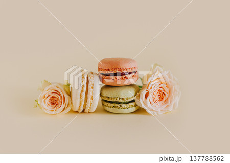 Tasty french macarons with tender rose flowers on a peach pastel background. 137788562