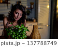 Woman caring for basil leaves, Closeup of hands adjusting herb plant, An indoor scene showing woman carefully managing her fresh herb garden with focus and care 137788749