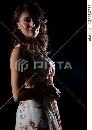 Stylish woman stands confidently with artistic lighting and warm hues, Graceful female figure exhibits calm confidence under artistic backlight in studio setting 137788757