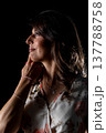 Woman planning carefully, Thoughtful female silhouette contemplating with quiet purpose, Woman in dim lighting carefully strategizing her next move with intent focus 137788758