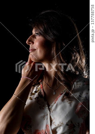 Woman planning carefully, Thoughtful female silhouette contemplating with quiet purpose, Woman in dim lighting carefully strategizing her next move with intent focus 137788758