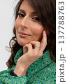Seated portrait caucasian woman wearing green dress, chin resting on hand, confident smile, polished nails, natural makeup, studio lifestyle scene, creative professional mood 137788763