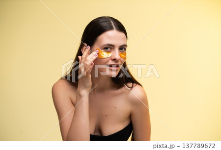 Young woman applying under eye patches for skincare and anti-aging hydration, getting beauty treatment and self-care for glowing, healthy skin, focusing on wellness routine Young woman applying under eye patches for skincare and anti-aging hydration, getting beauty treatment and self-care for glowing, healthy skin, focusing on wellness routine 137789672