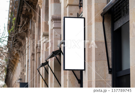 Blank vertical signage mockup displaying on a stone building facade, creating an outdoor advertising design template for storefront promotion and business branding Blank vertical signage mockup displaying on a stone building facade, creating an outdoor advertising design template for storefront promotion and business branding 137789745